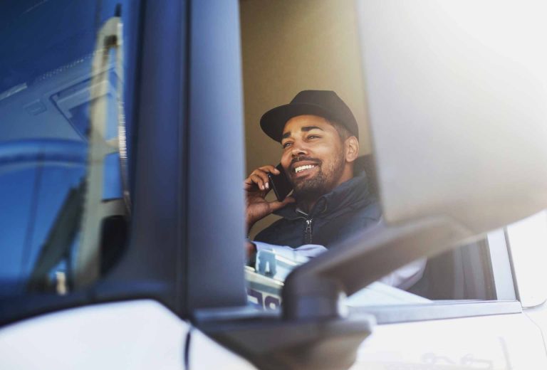 man holding his phone over his ear while smiling inside a truck